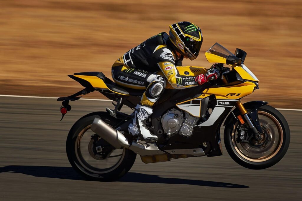 This is a Yamaha R1 racing down a track doing a small wheelie part of a guide to buying a used Yamaha R1.