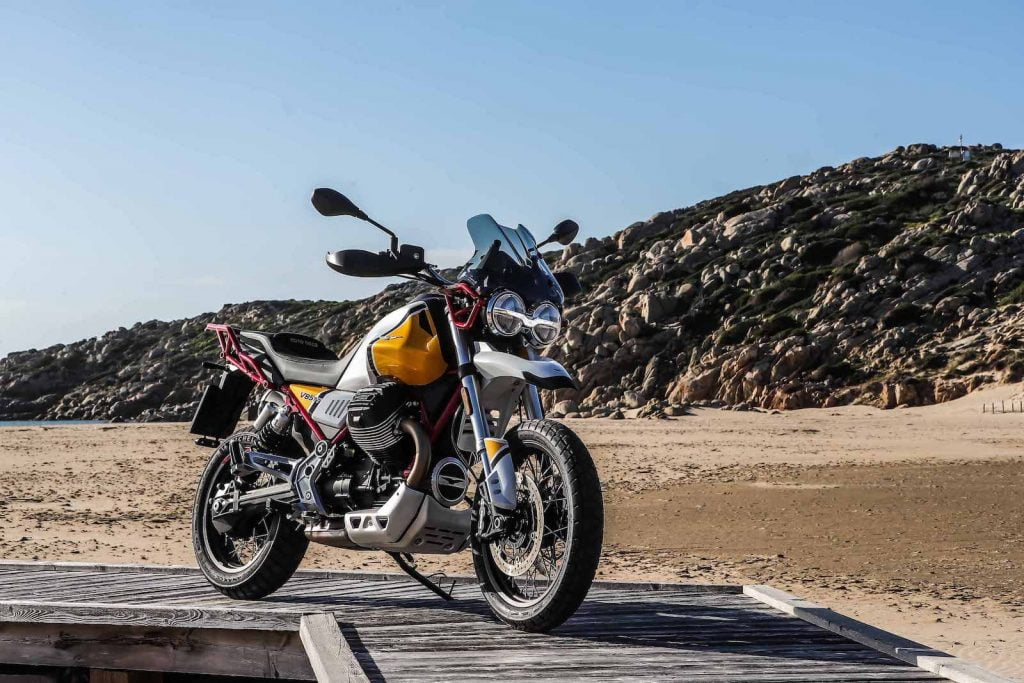 Moto Guzzi V85 TT on boardwalk hill in background Giallo Sahara