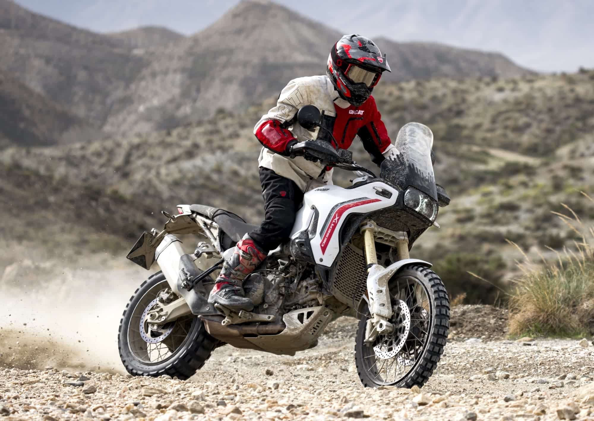 Ducati DesertX Buyer's Guide 11 2026 Ducati DesertX V2 being ridden standing on a loose rocky trail