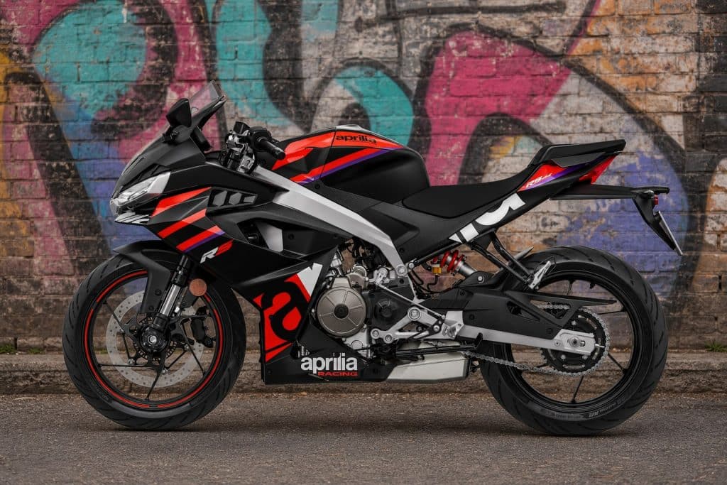 Aprilia RS 457 — More than the Sum of its Parts 1 Aprilia RS 457 Racing Stripes in left-side profile against a graffiti-covered brick wall