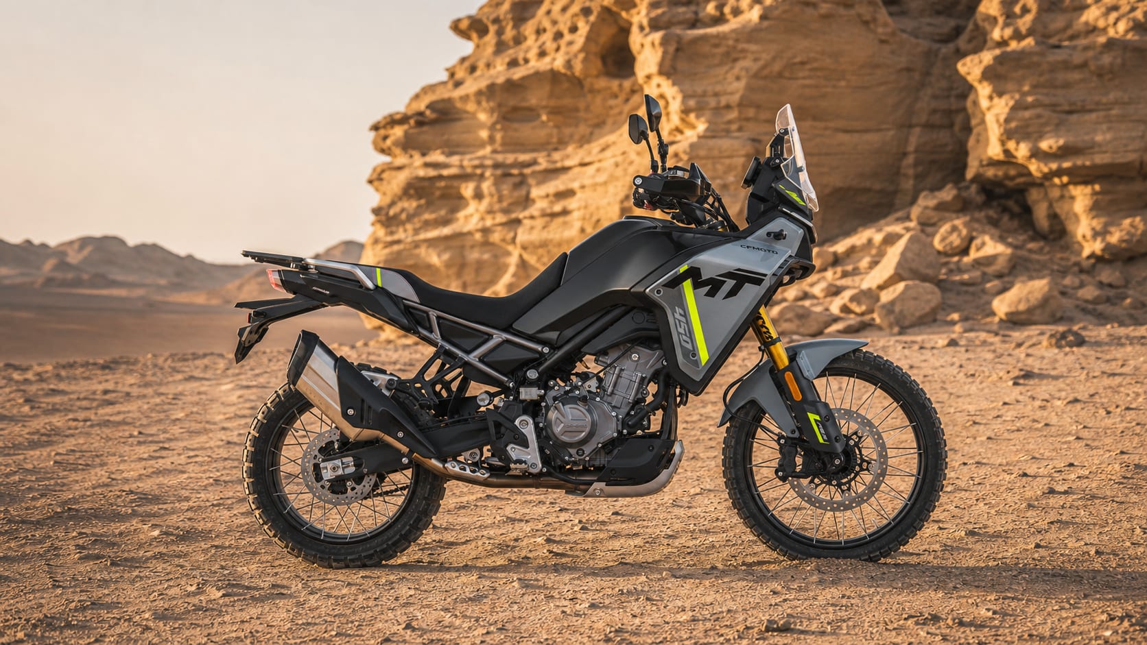 CFMOTO 450MT Review — Popular for a Reason 1 CFMOTO 450MT in Tundra Grey on desert sand beside a sandstone formation
