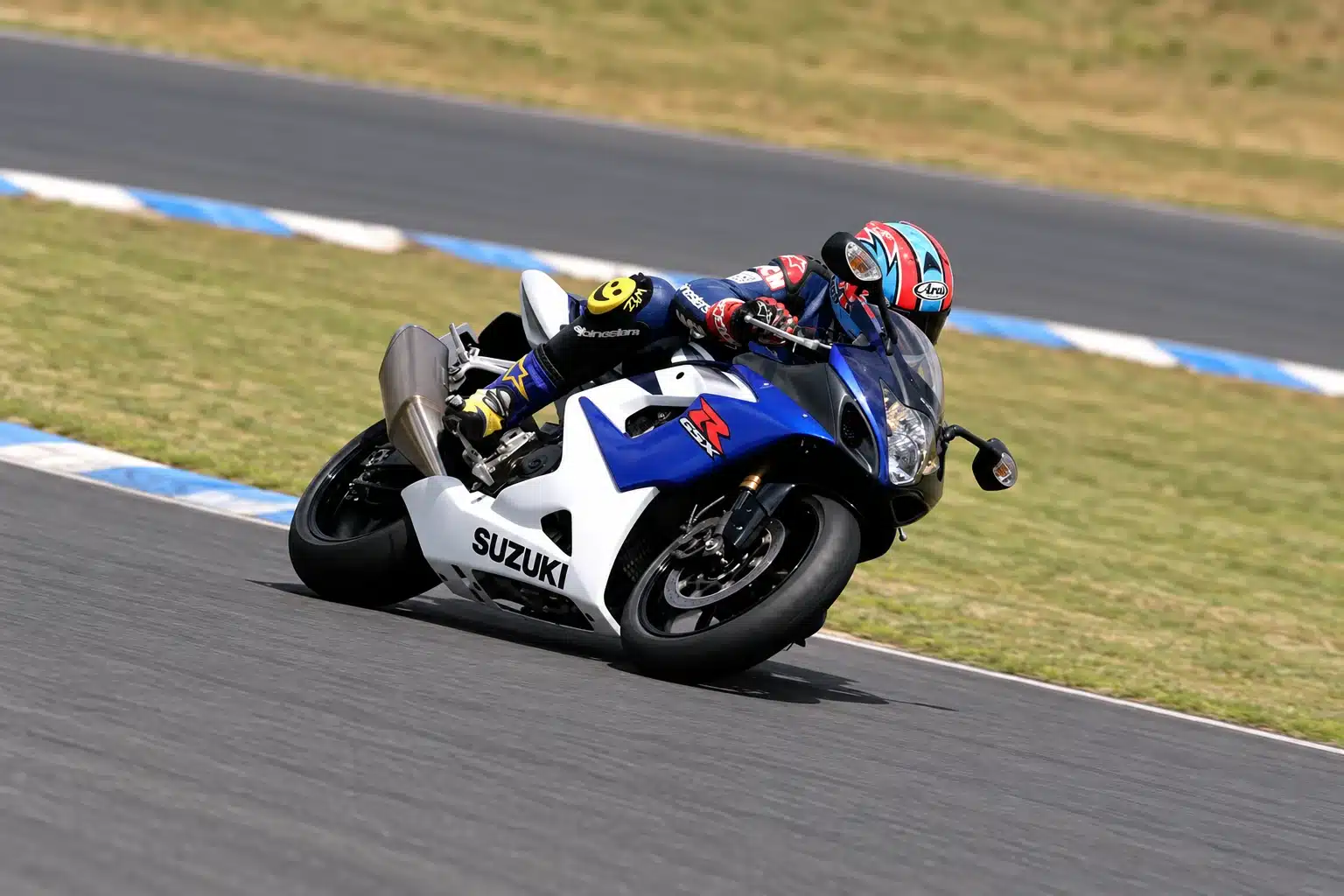 The K5 Suzuki GSX-R1000 — The Legend of Godzilla 4 Blue and white 2005 Suzuki GSX-R1000 K5 leaned over on a racetrack