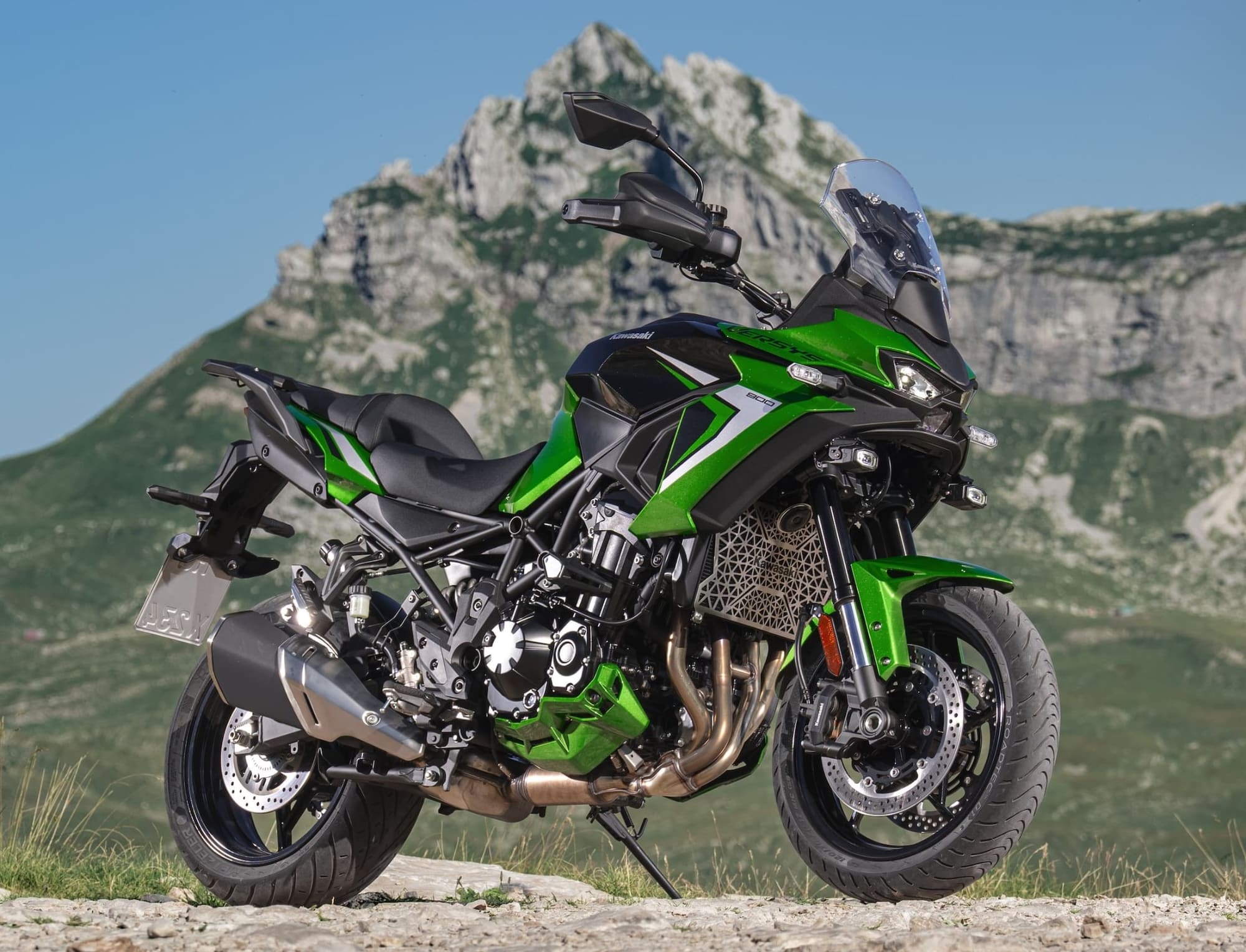 2027 Kawasaki Versys 900 — Radar Cruise Comes to the Middleweights 2 Green Kawasaki Versys 900 SE parked against mountain scenery